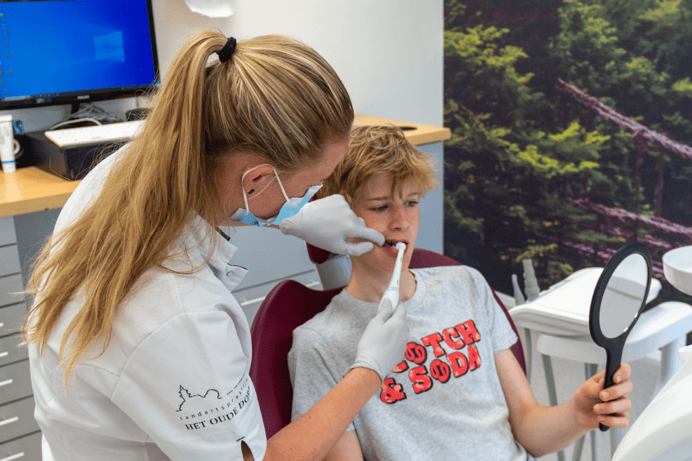 Tandarts helpt jonge patiënt met behandeling.